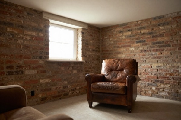 Cozy finished basement living room with exposed brick and natural light.
