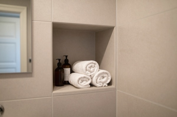 Recessed tiled niche holding towels and toiletries