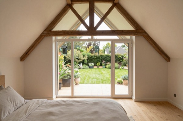 Finished bedroom extension interior with vaulted ceiling and garden view.