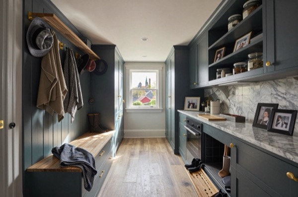 Boot room and pantry with dark teal cabinetry, marble worktop, and wooden bench.