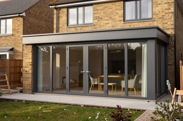 Modern house extension with glass doors and windows, integrated with a garden.