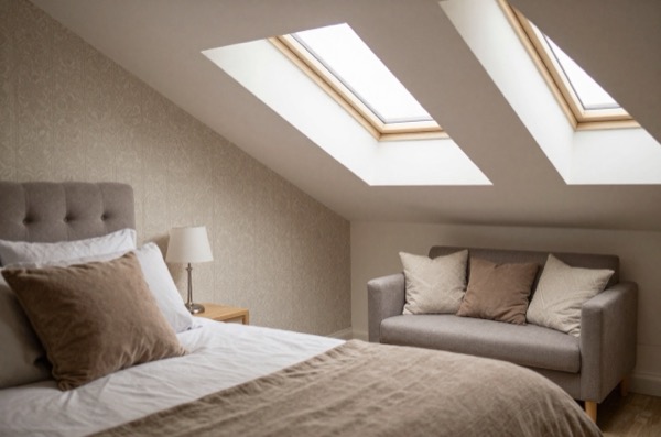 Cozy loft conversion bedroom with sitting area and patterned wallpaper