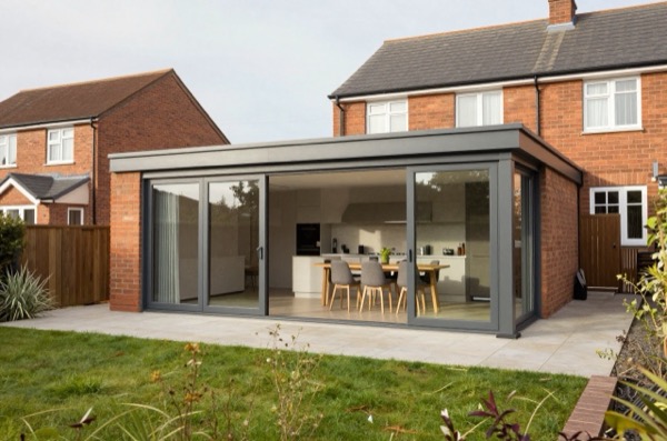 Modern single-storey extension with glass doors, contemporary kitchen, and paved patio.
