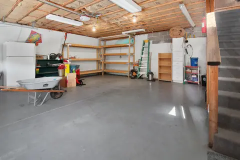 Spacious garage interior with storage shelves, tools, and a wheelbarrow, ideal for home organization.