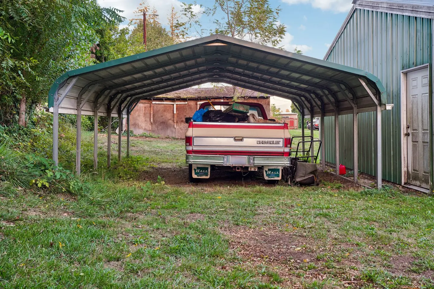 A Chevrolet truck loaded with items parked under a metal carport.