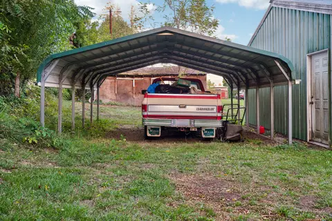 A Chevrolet truck loaded with items parked under a metal carport.