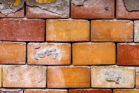 Detailed close-up of an aged brick wall, showcasing texture and construction pattern.