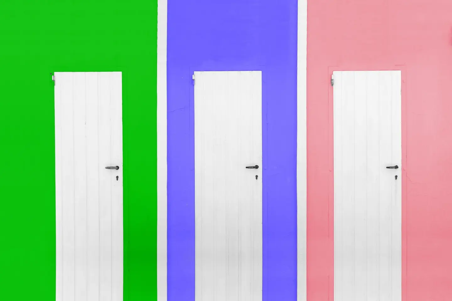 Three white doors against bright green, blue, and pink walls depicting modern style.