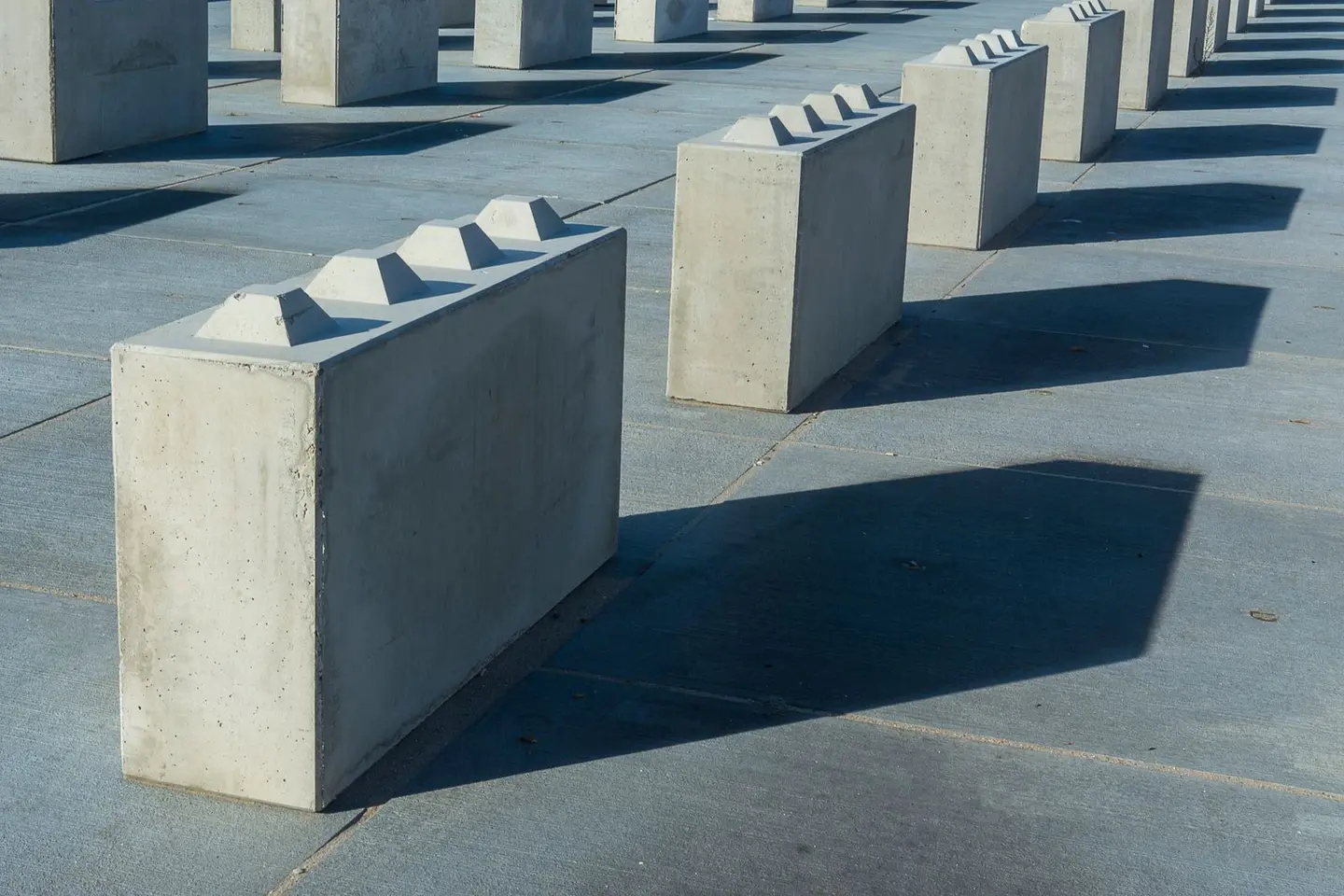 Artistically arranged concrete blocks casting shadows on the ground.