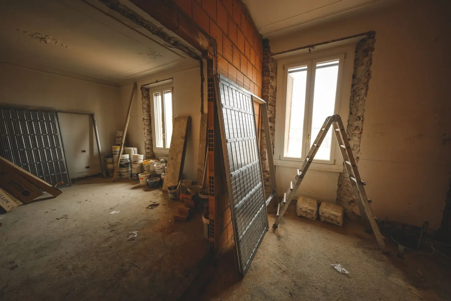 Interior view of a room under renovation with construction materials and a ladder.