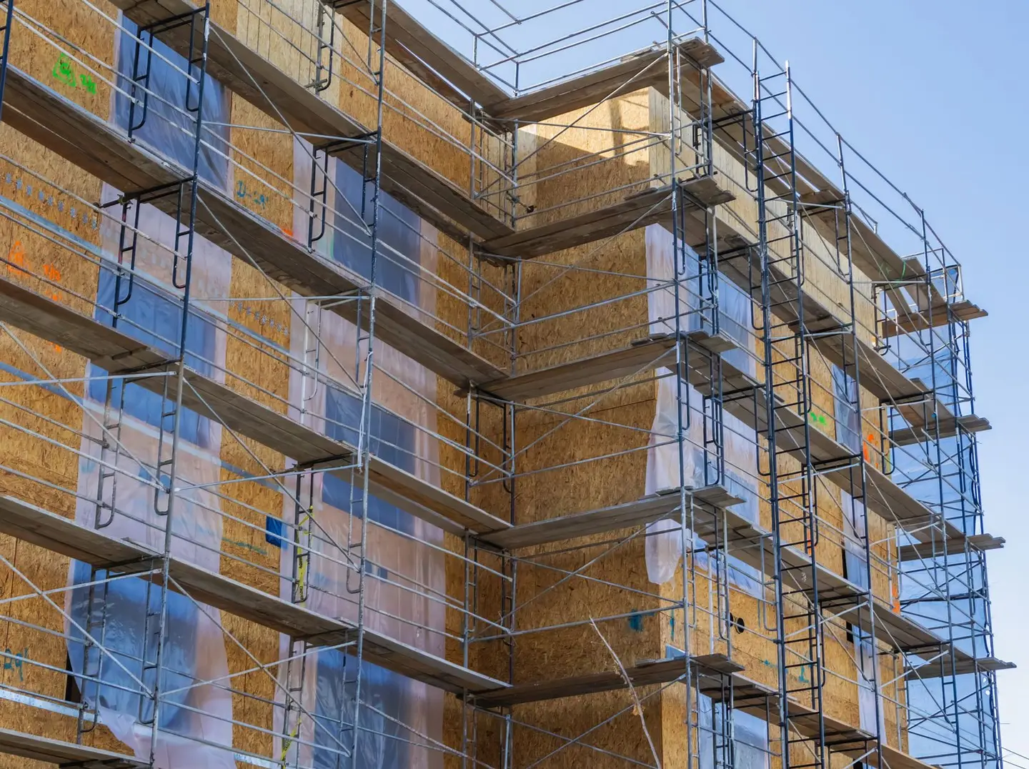 A high-rise building with scaffolding for construction and repair work under a clear sky.