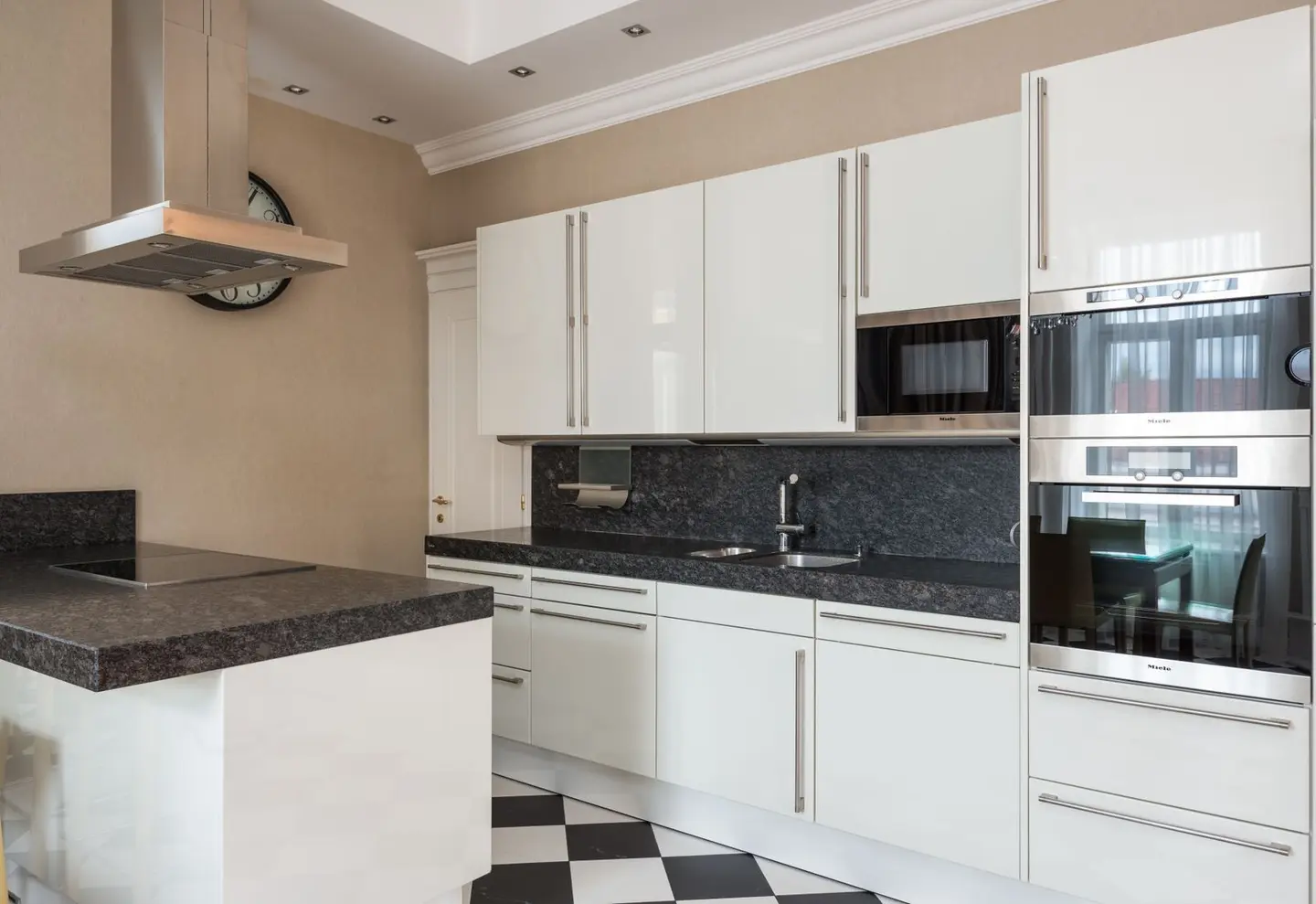 Interior of modern kitchen made in minimalist design with glossy cabinets and built in microwave oven and hob on counter under hood