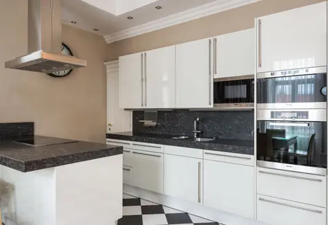 Interior of modern kitchen made in minimalist design with glossy cabinets and built in microwave oven and hob on counter under hood