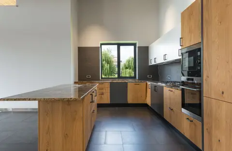 Interior of spacious kitchen with wooden counter located in middle with built in hob appliances and many cabinets