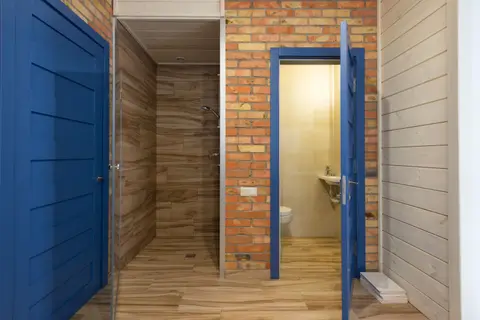 Contemporary bathroom interior with wooden and brick materials, featuring blue doors and a shower area.