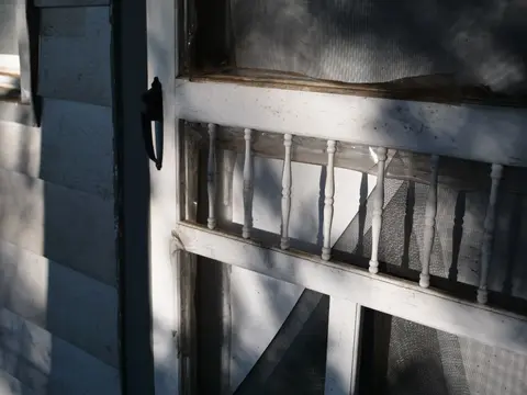 Close-up of rustic wooden door showing sunlight and texture.