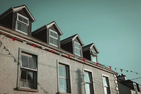 Quaint residential building with dormer windows and decorative bunting under clear skies.
