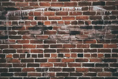 A close-up of a red brick wall with white paint drippings, offering a textured urban background.