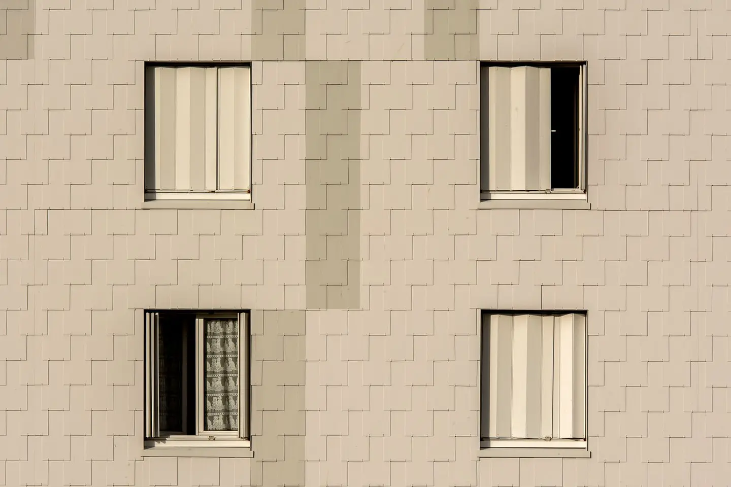 Close-up of a modern apartment building facade with symmetrical windows and beige cladding.