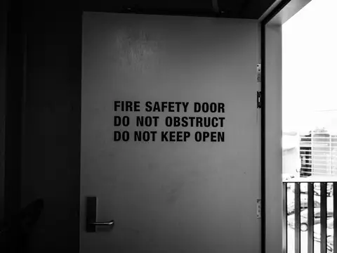 Black and white image of fire safety door with warning instructions.
