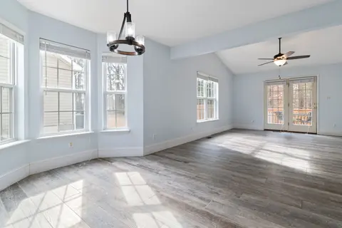 Bright empty living room with wooden floor and ceiling fan, ideal for interior design use.
