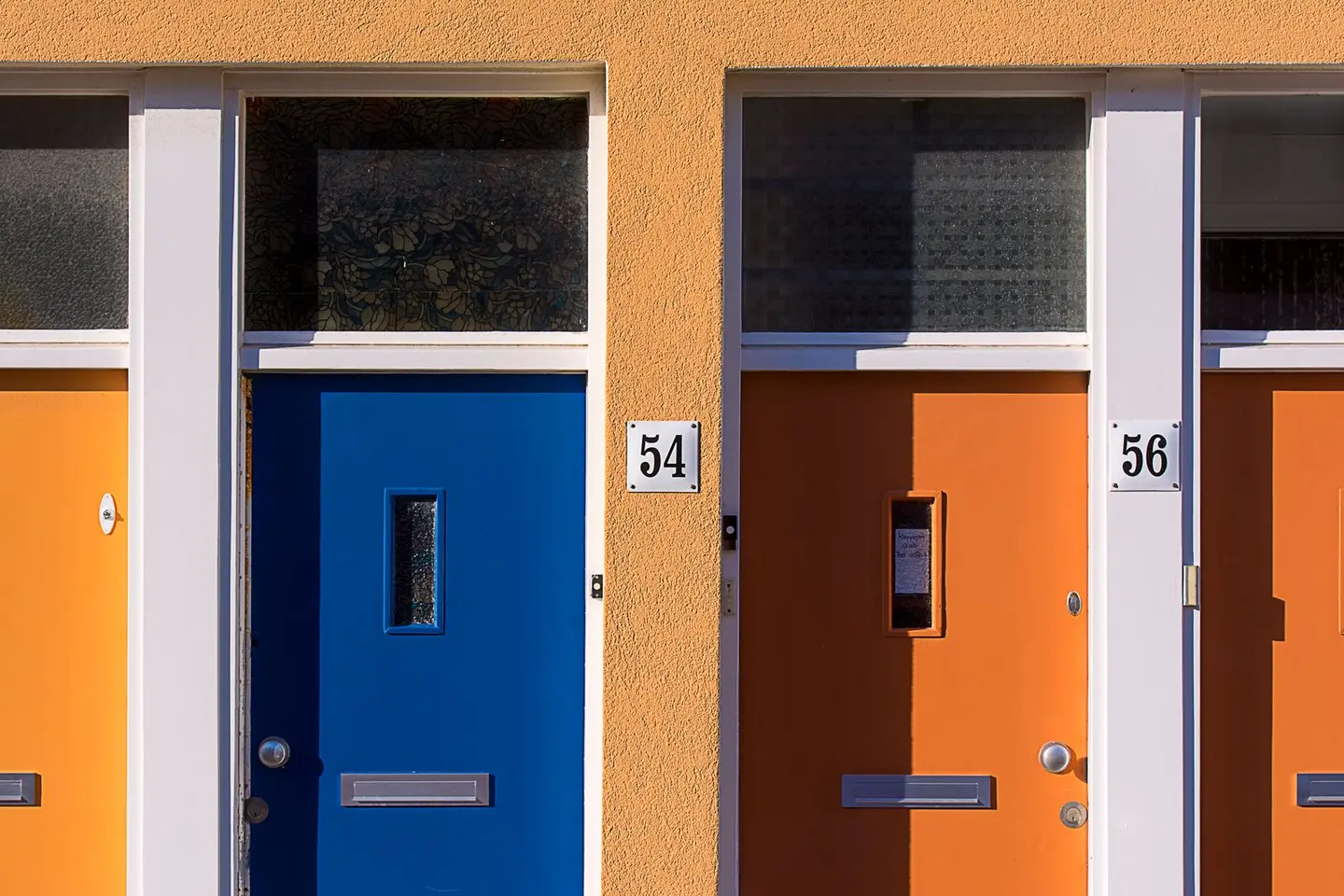 Brightly coloured doors with numbers 54 and 56 on a modern building facade.