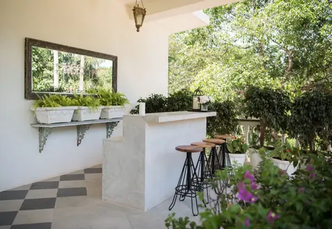 Stylish outdoor bar with stools and lush greenery, perfect for relaxation in a garden setting.