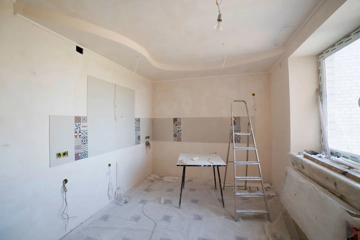 Spacious kitchen under renovation with ladder and tools, showcasing a fresh new design.