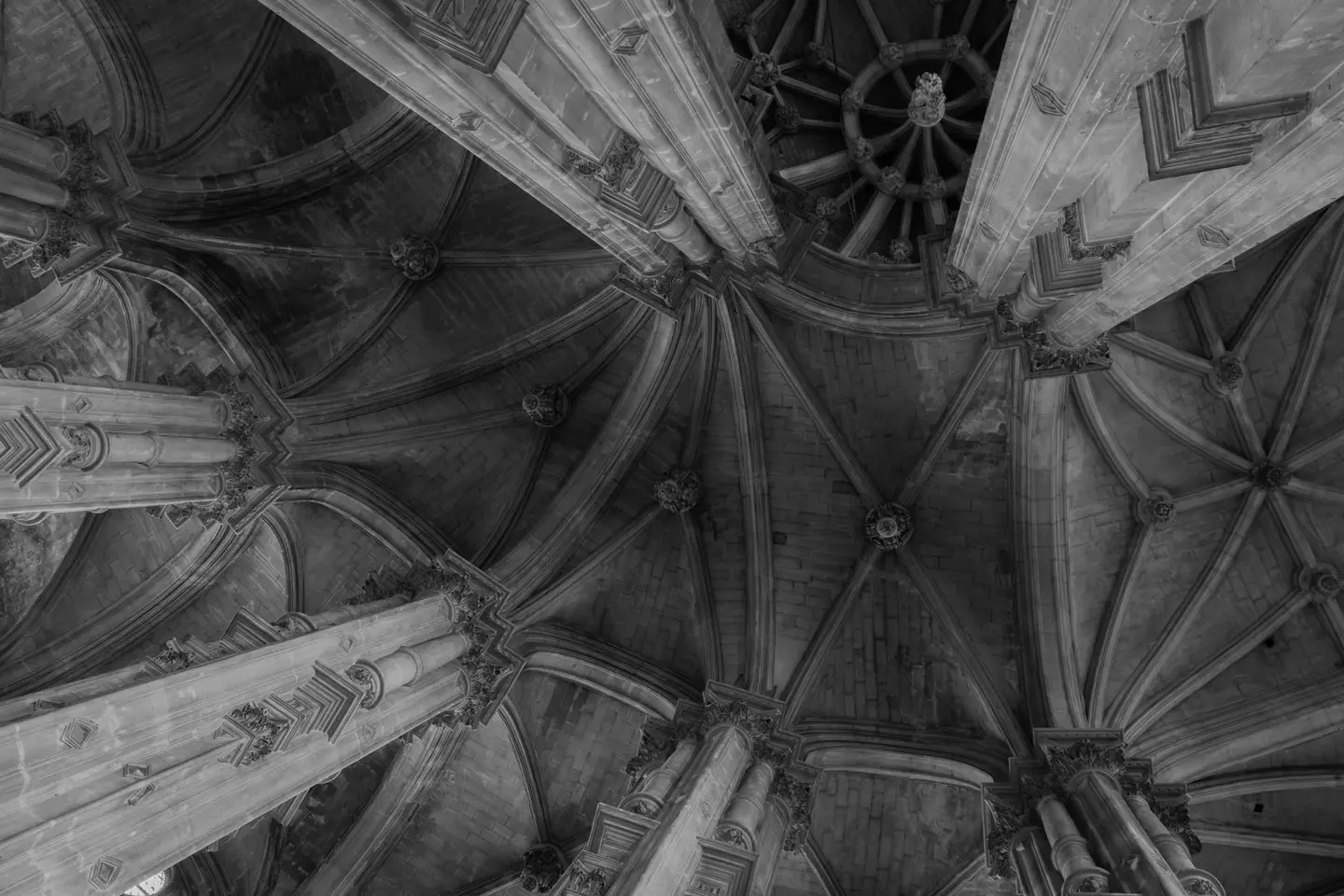 Black and white photo of a gothic vaulted ceiling with intricate stone columns.