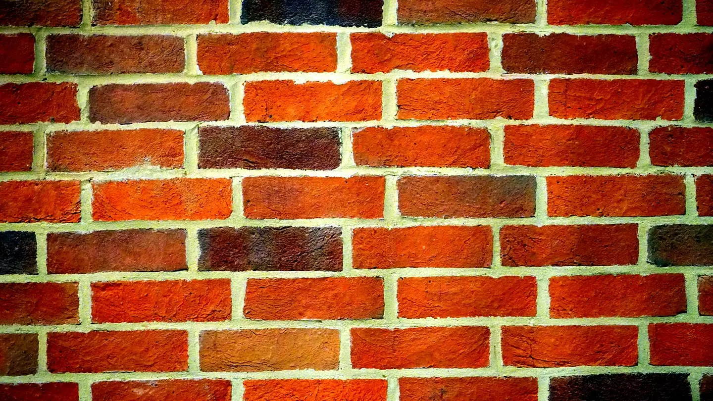 Close-up of a red brick wall showing distinct mortar joints and rough texture.