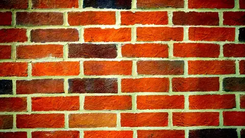 Close-up of a red brick wall showing distinct mortar joints and rough texture.