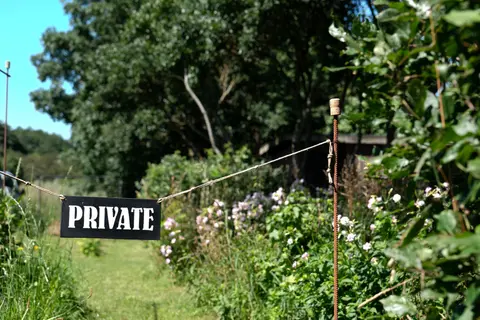 Sign reading 'PRIVATE' in a lush garden setting, conveying privacy and exclusivity.