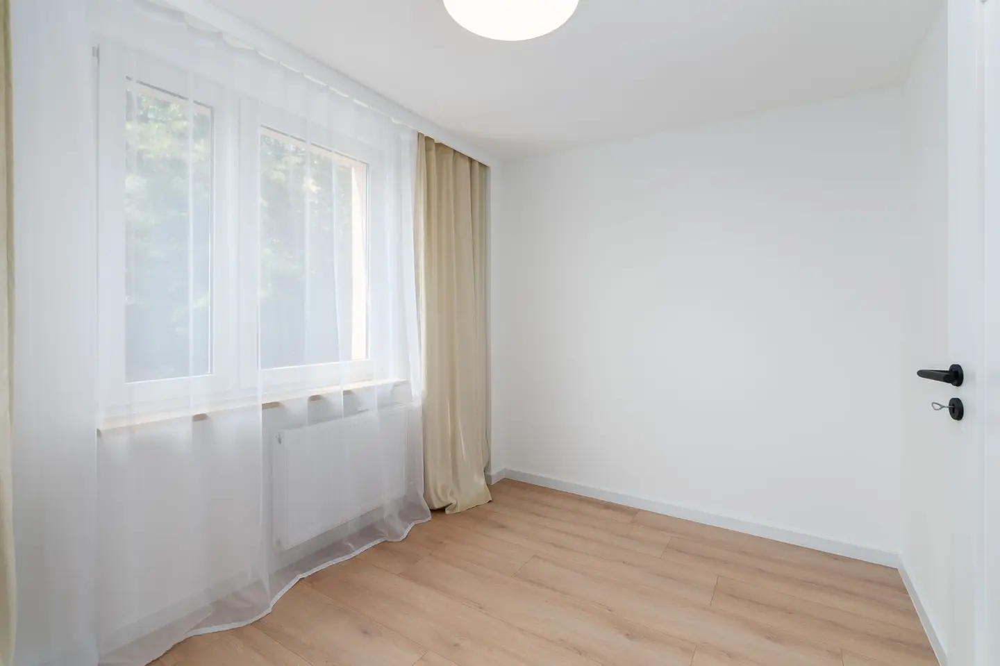 Bright and empty room with sheer curtains and wooden floor, perfect for interior design ideas.