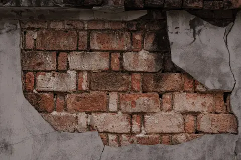 Close-up of a weathered wall with exposed rustic brickwork, showcasing a textured urban decay.