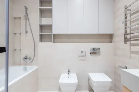 Interior of modern light bathroom with bidet and toilet next to sink and bath