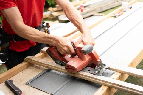 Carpenter cutting wood with a circular saw at an outdoor construction site, showcasing craftsmanship.