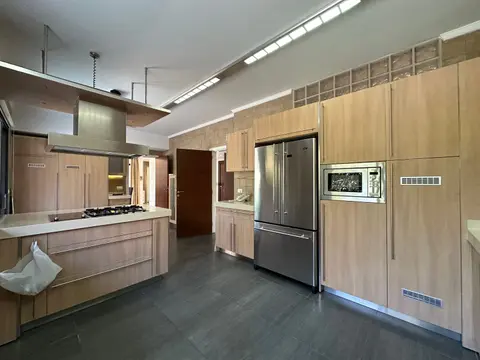 Spacious modern kitchen featuring sleek wooden cabinets, stainless steel appliances, and ample lighting.