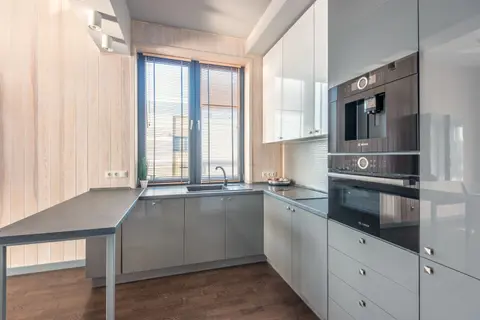 Stylish modern kitchen interior with sleek cabinets and natural light through a large window.