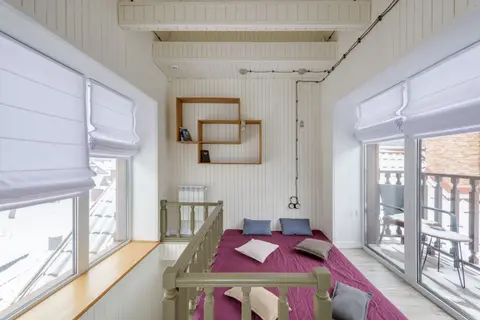 Modern interior design featuring loft bed, pillows, and geometric shelves by windows.