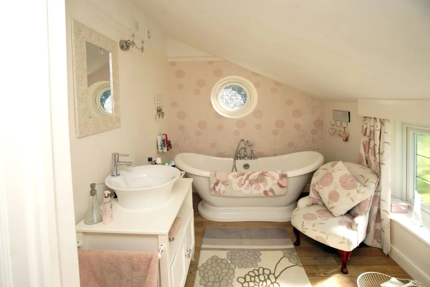 Charming attic bathroom featuring a freestanding tub and floral accents, perfect for a relaxing retreat.