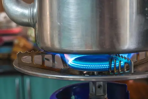 A detailed image showing a gas hob burner with a pot above, highlighting kitchen heat and flame.