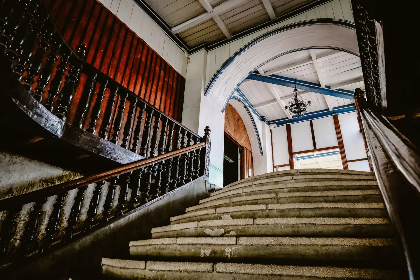 Elegant staircase with ornate wooden railings and arches in a historic interior setting.