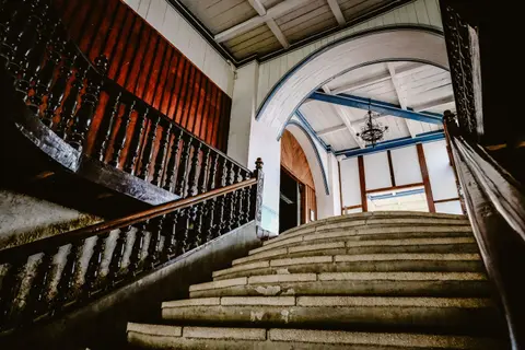 Elegant staircase with ornate wooden railings and arches in a historic interior setting.