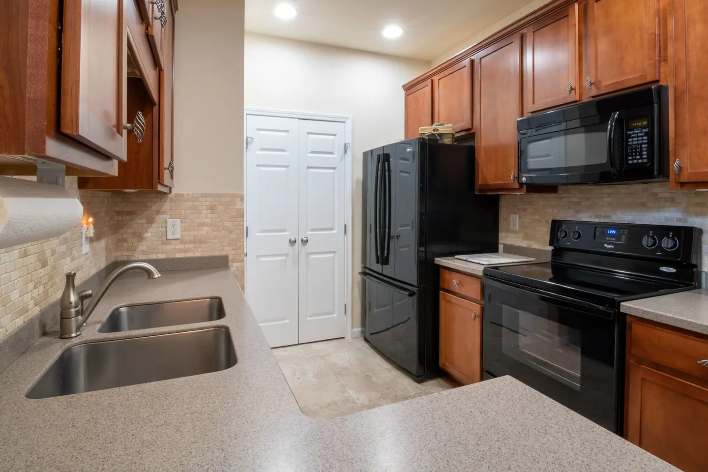 A contemporary kitchen featuring wooden cabinets, modern appliances, and a marble worktop.