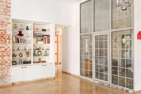 Bright interior room with floor-to-ceiling glass doors and decorative shelves.