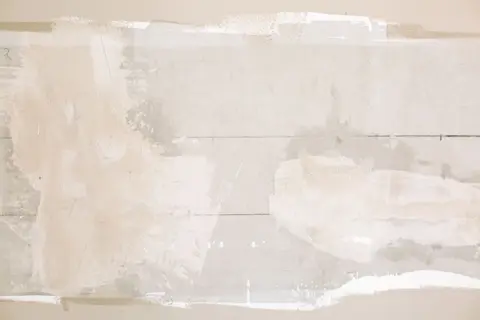 Close-up of an unfinished wall showing plaster and paint textures in a home renovation.