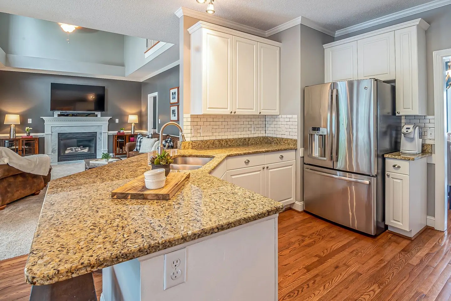 Luxurious open-concept kitchen with granite worktops and modern appliances, flowing into a cozy living room with a fi