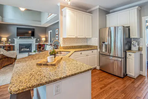 Luxurious open-concept kitchen with granite worktops and modern appliances, flowing into a cozy living room with a fi
