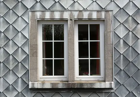 Closeup of a modern double window set in a textured shingle facade, highlighting architectural details.