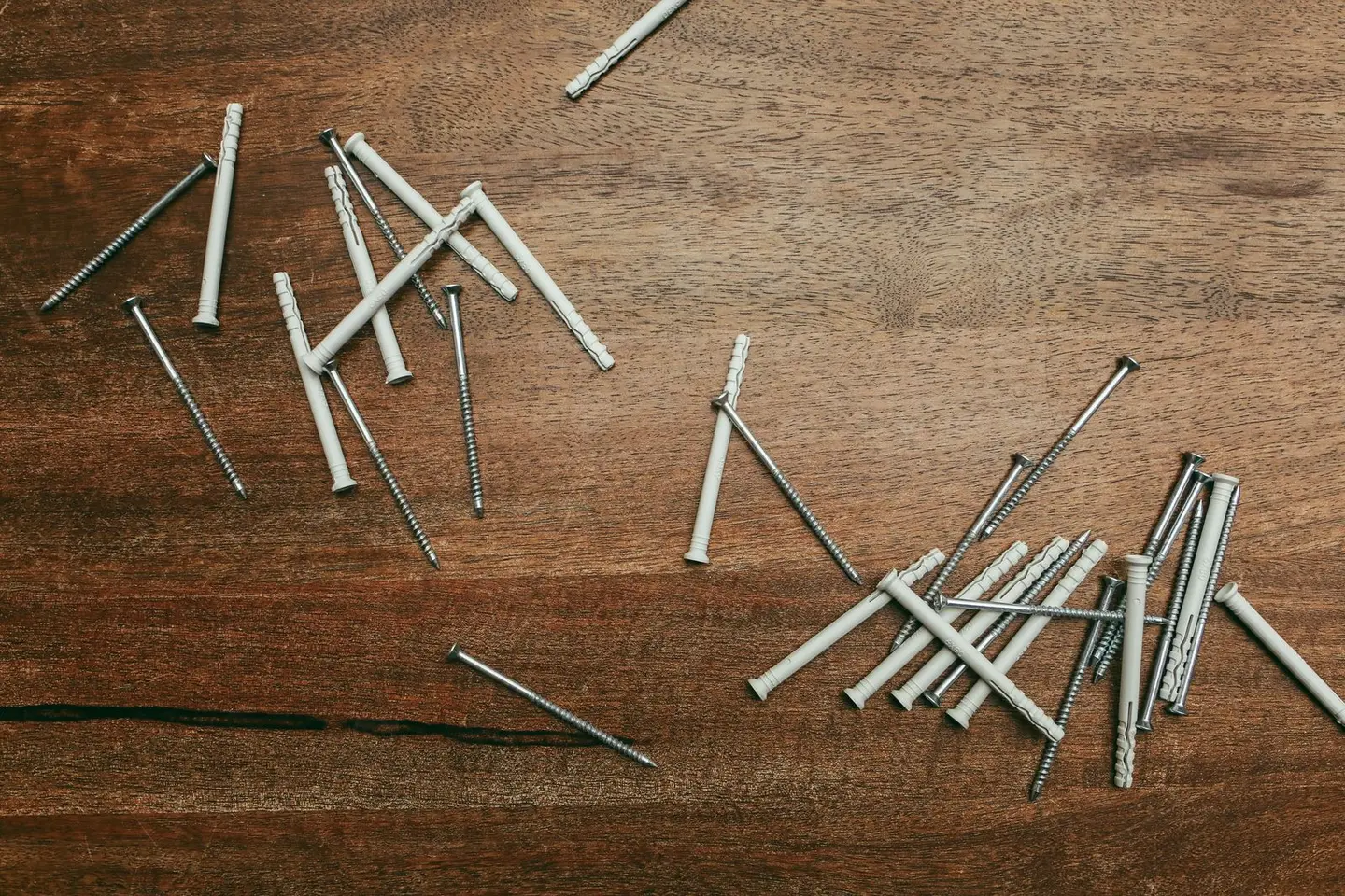 Close-up of nylon anchors and screws scattered on a wooden surface, perfect for DIY projects.